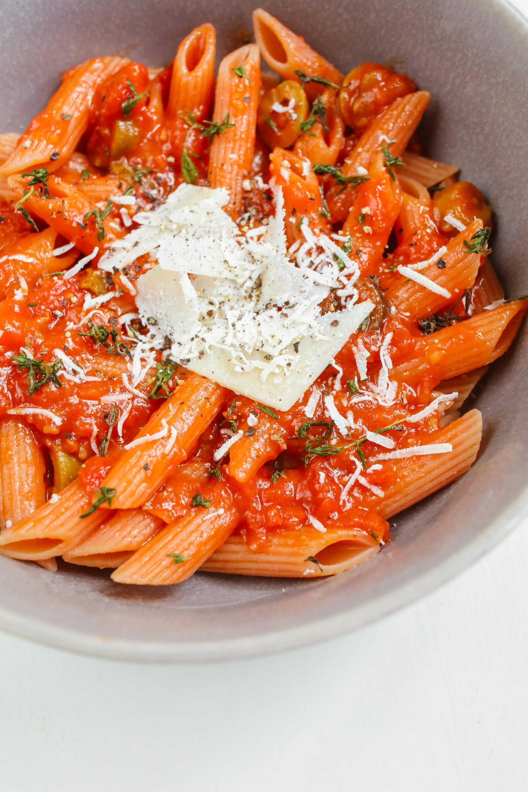 Home Close-up of penne pasta in rich tomato sauce topped with cheese, perfect for an Italian meal.